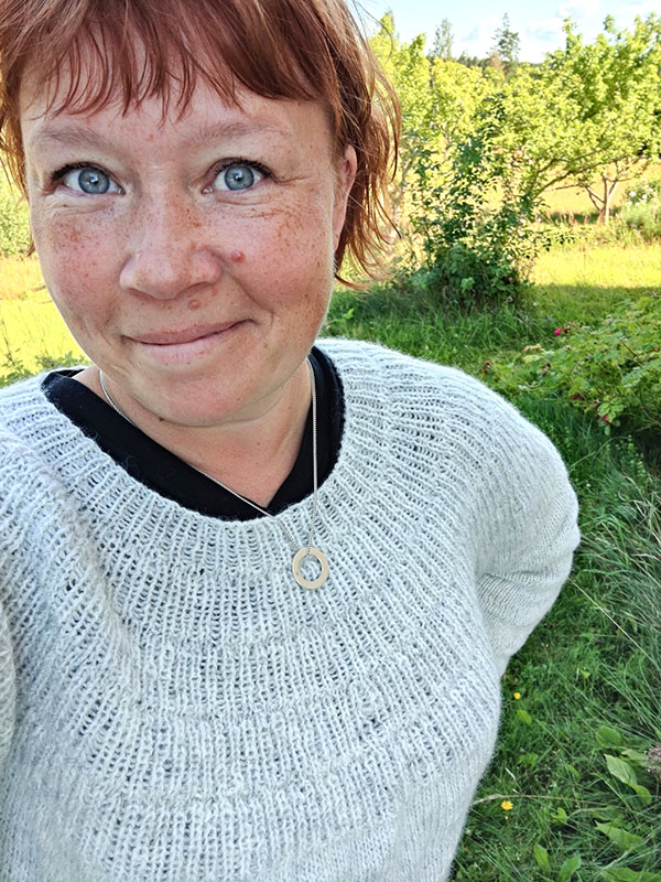En selfie där jag har på mig den ljusgrå stickade tröjan. Jag har rött hår och blåa ögon och ser glad ut.